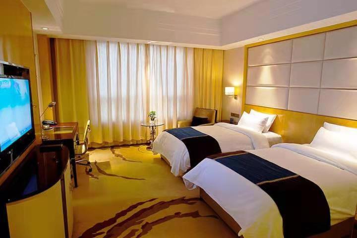 Nanjing Lafei Hotel Lukou Airport Branch في نانجينغ: غرفة فندقية بسريرين وتلفزيون بشاشة مسطحة