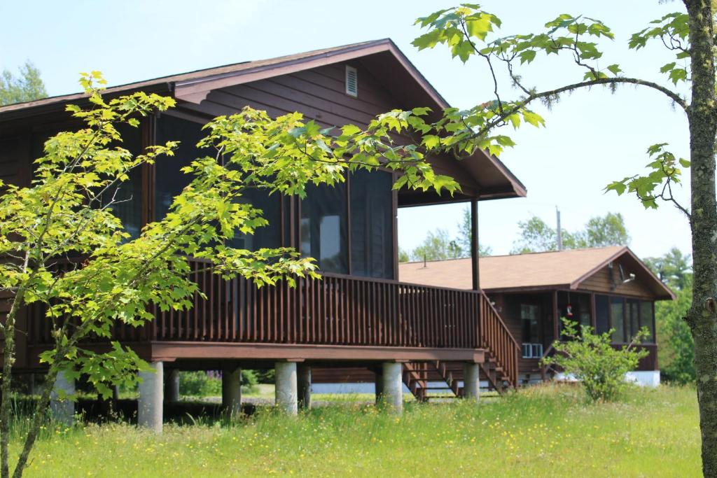 a wooden house in the woods with trees at 1 and Only Riverside Accommodations in Sable River