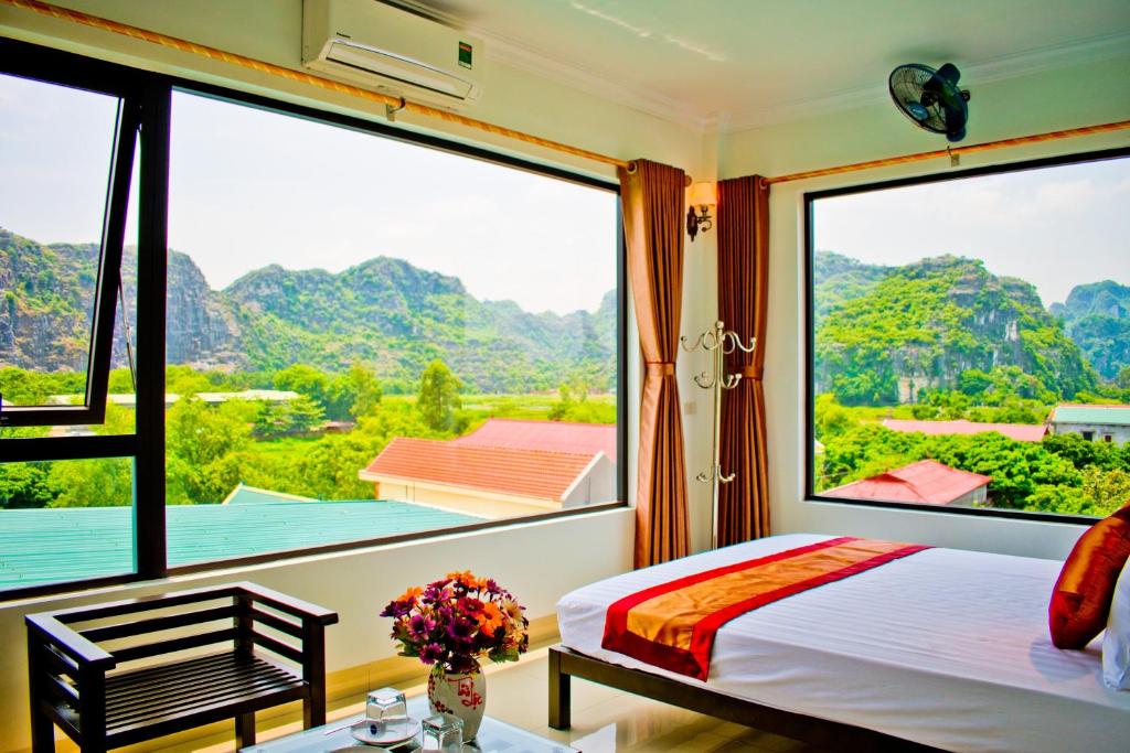 a bedroom with a bed and large windows with mountains at Trang An Mountain View Homestay in Ninh Binh