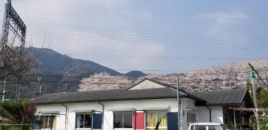 a white house with mountains in the background at KAFUU guesthouse+cafe in Kashiba