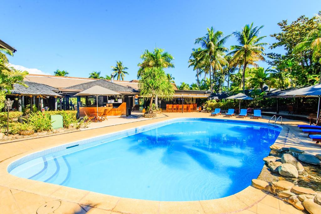 a large swimming pool in a resort with palm trees at Tanoa International Hotel in Nadi