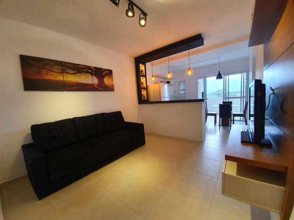 a living room with a black couch and a table at Condomínio completo em Ubatuba a 300 metros da praia in Ubatuba