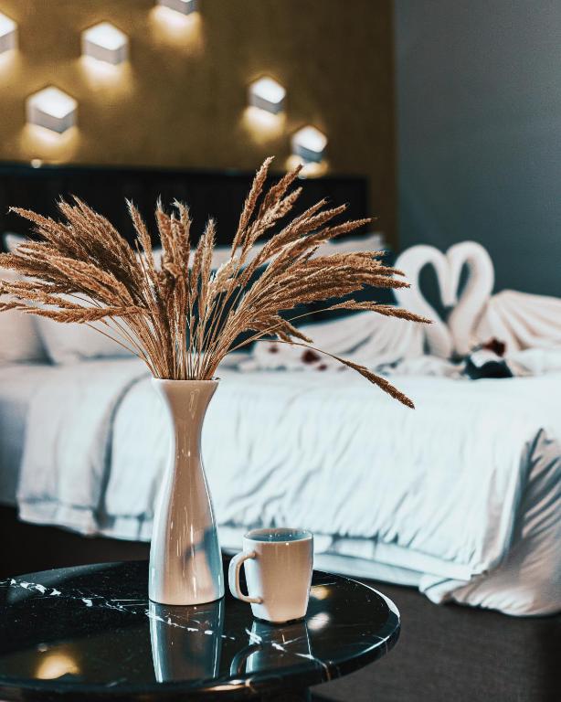 a vase with dry grass on a table next to a bed at Aspira D'Andora Sukhumvit 16 - Asoke in Bangkok