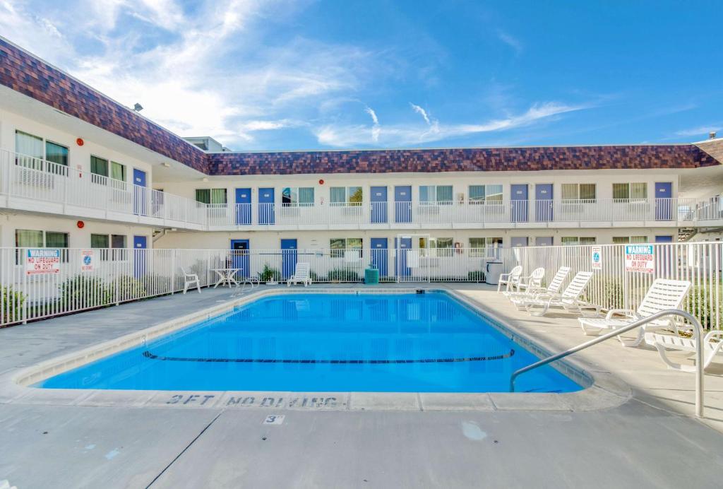 a swimming pool in the courtyard of a building with chairs at Motel 6-Moses Lake, WA in Moses Lake