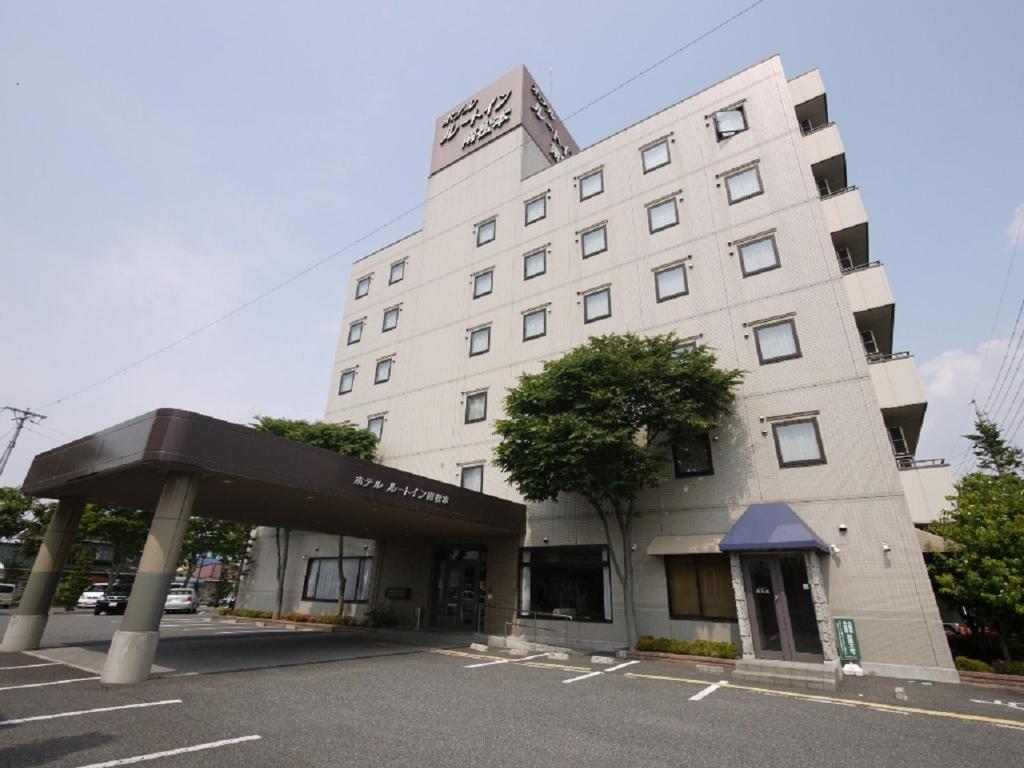 a large white building with a canopy in front of it at Hotel Route-Inn Court Minami Matsumoto in Matsumoto