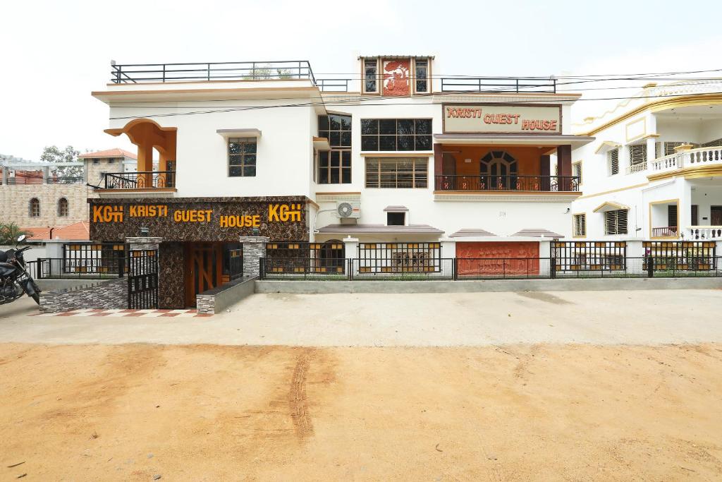 un bâtiment blanc avec un panneau devant lui dans l'établissement Kristi Guest House, Shantiniketan, à Santiniketan