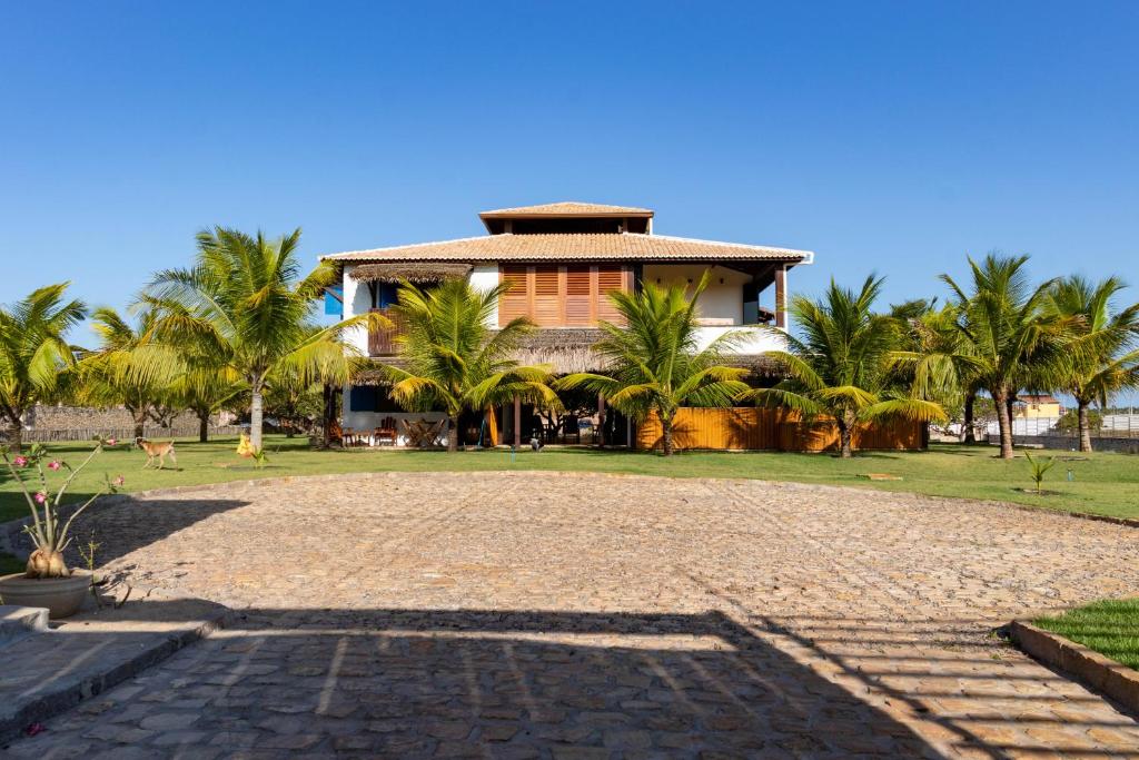 a building with palm trees in front of a driveway at Casa Corveta in São Miguel do Gostoso