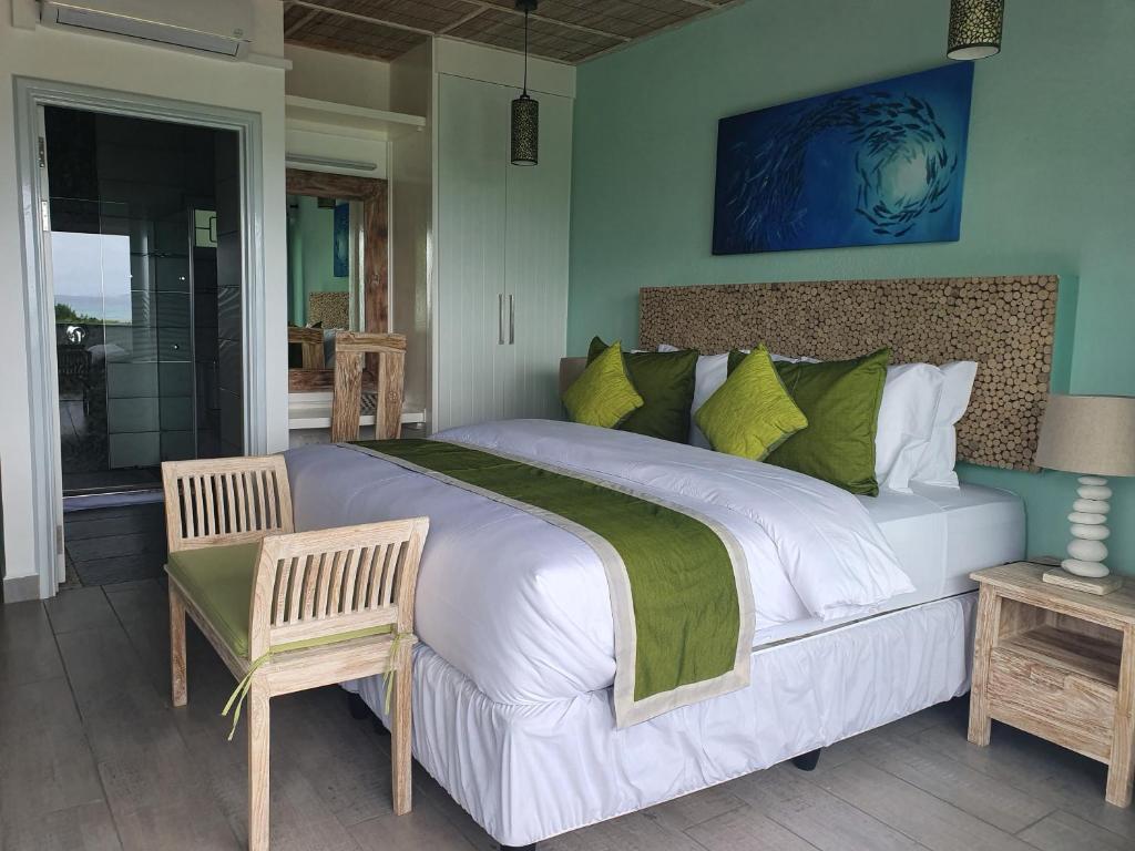 Bord Mer Luxury Apartments في لا ديج: غرفة نوم بسرير ابيض كبير مع مخدات خضراء