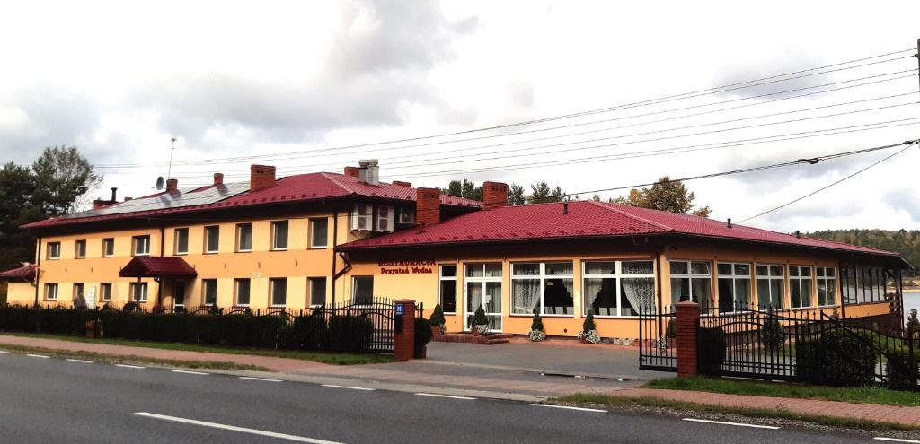ein Gebäude mit rotem Dach auf einer Straße in der Unterkunft Przystań Wodna Brody in Styków