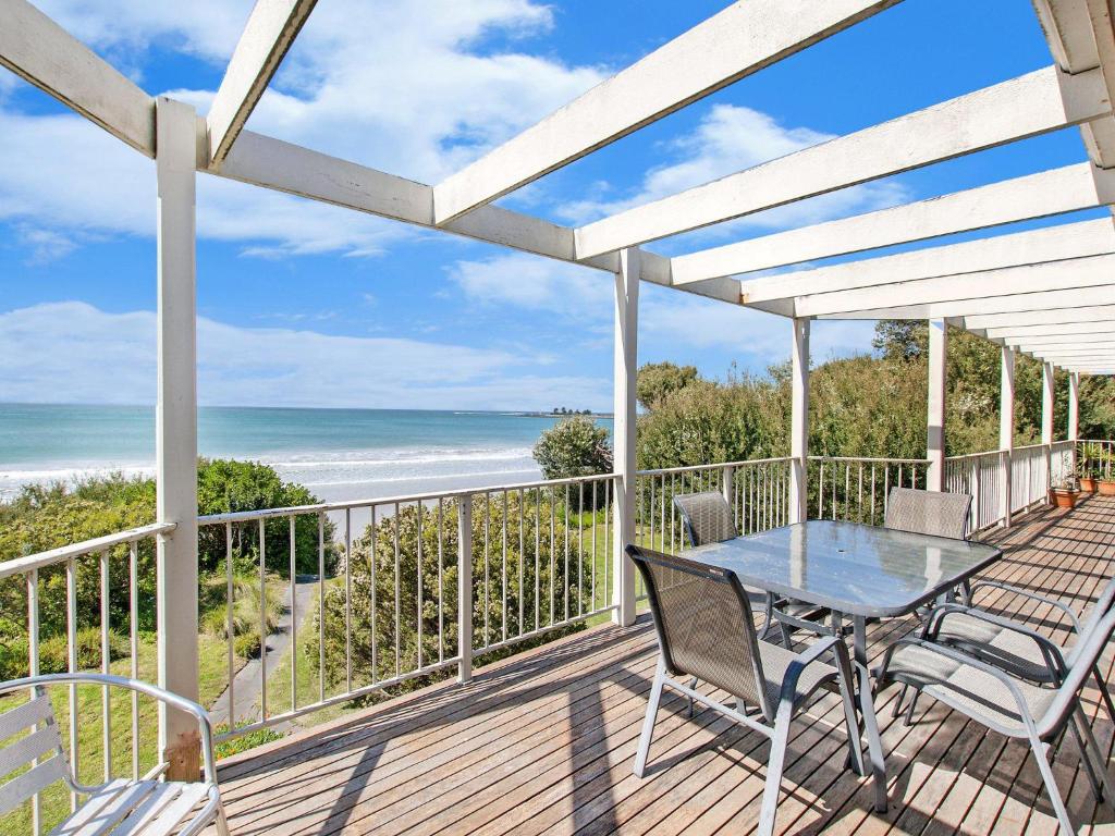 eine Terrasse mit einem Tisch, Stühlen und Meerblick in der Unterkunft East Beach House in Port Fairy