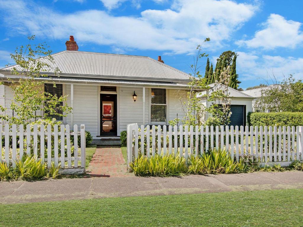 a white picket fence in front of a white house at Kinsale Cottage in Port Fairy