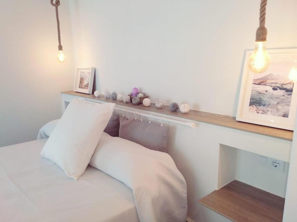 a bedroom with a white bed and a wooden shelf at 4nudos playa in San José