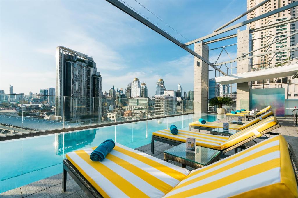 曼谷的住宿－阿卡拉飯店，阳台设有黄色和白色的椅子和游泳池。