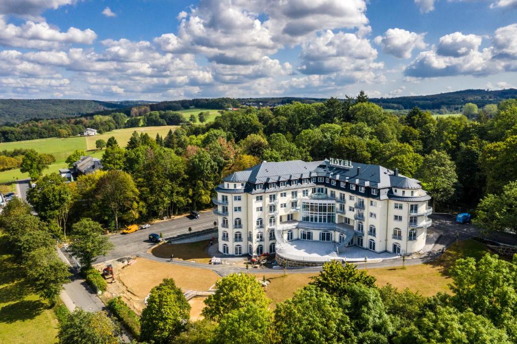 an aerial view of a large white building with trees at Parkhotel Hachenburg in Hachenburg