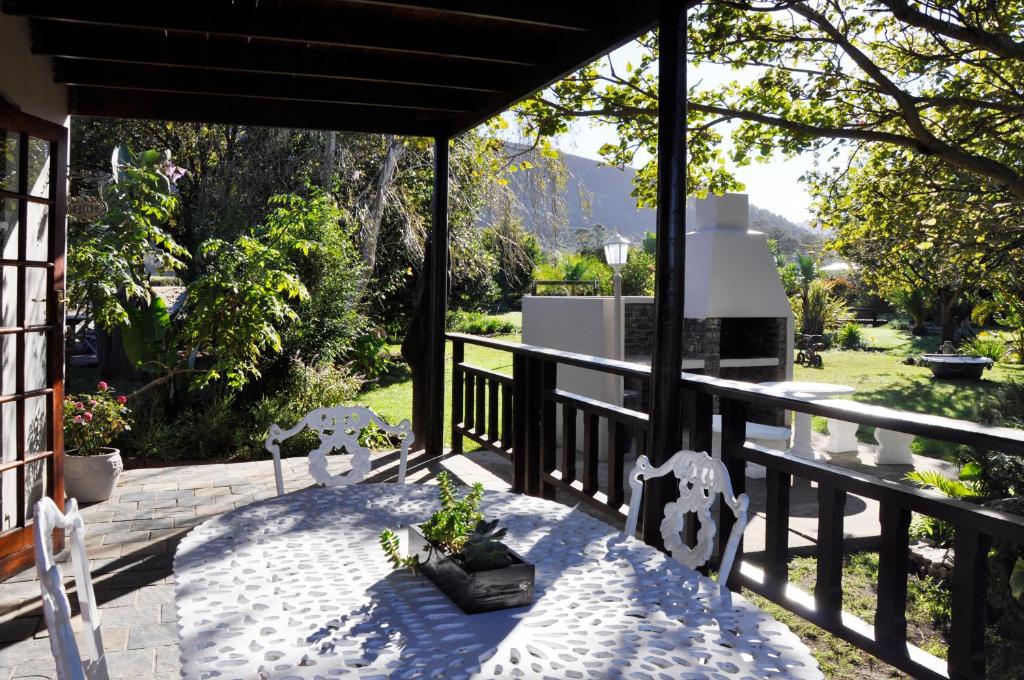 a patio with a table and chairs on a porch at Tsitsikamma Gardens Self-Catering Cottages - Cottage #2 in Sanddrif