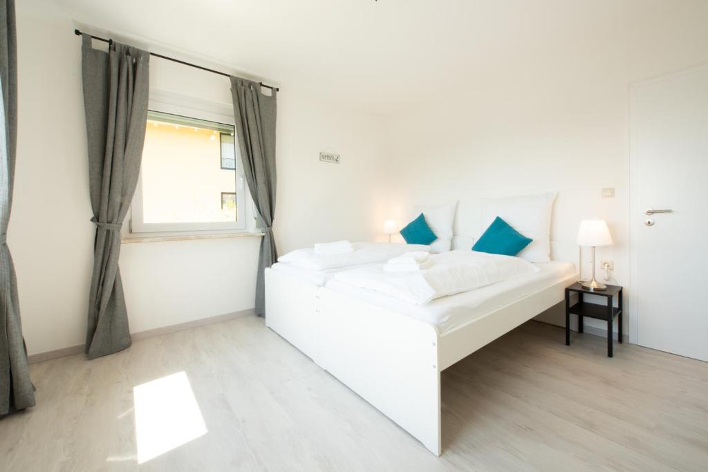 a white bedroom with a white bed and a window at FeWo Meersburg in Meersburg