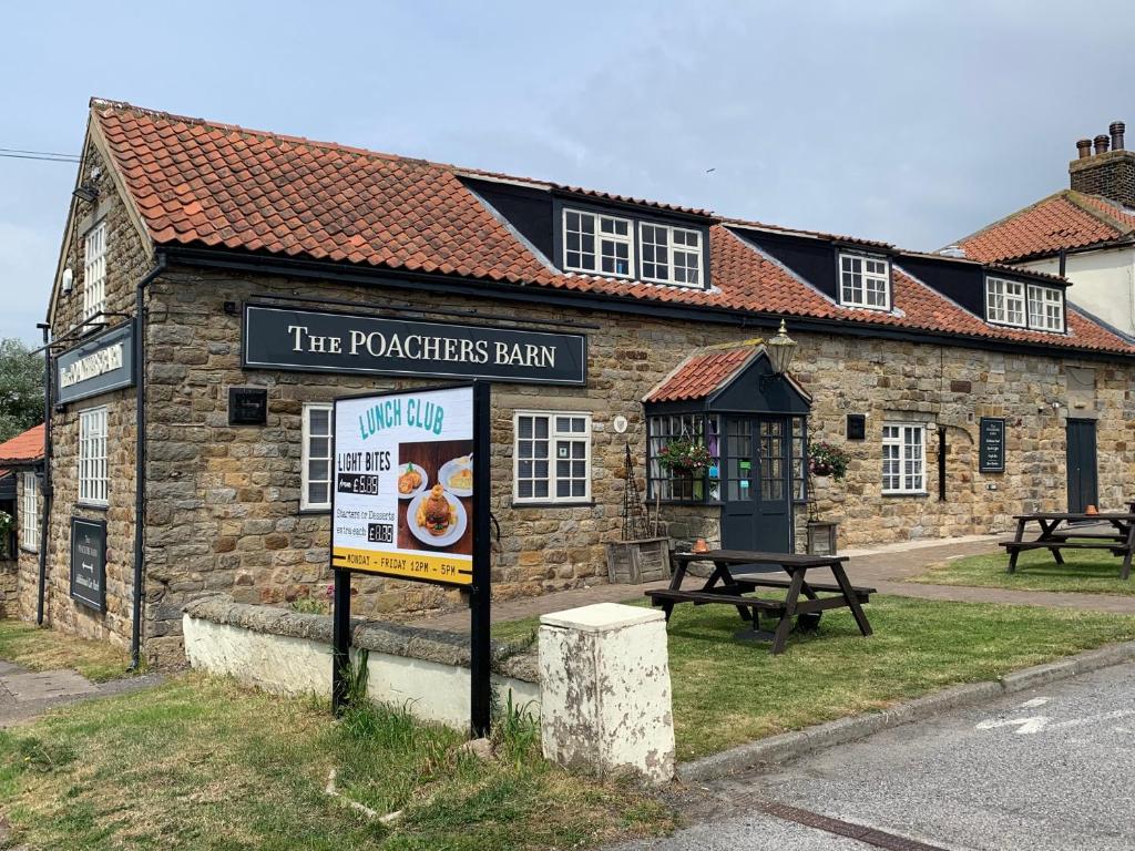 a restaurant with a sign in front of a building at Poacher's Barn in Cayton