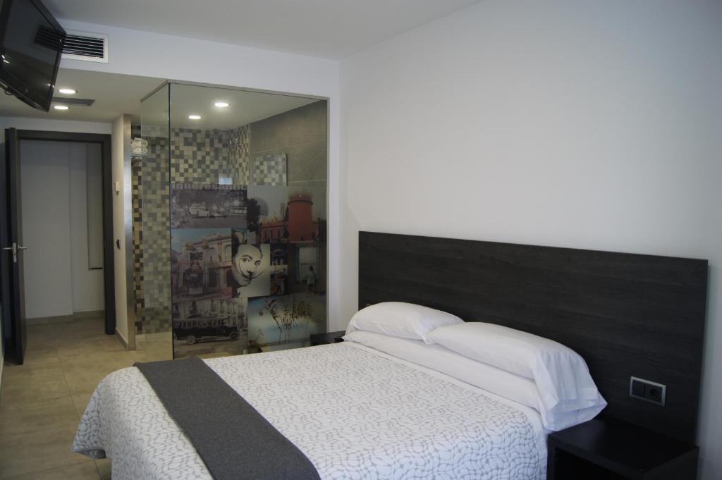 una camera con un grande letto e uno specchio di Hostal Sanmar a Figueres