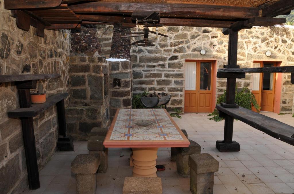 un patio con una mesa de madera en un edificio de piedra en Pantelleria Serraglia, en Pantelleria