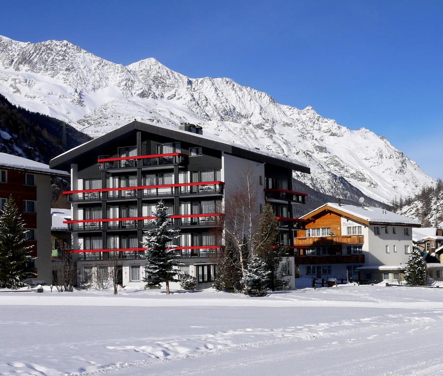 a building in front of a snow covered mountain at Hotel Alpenhof in Saas-Almagell