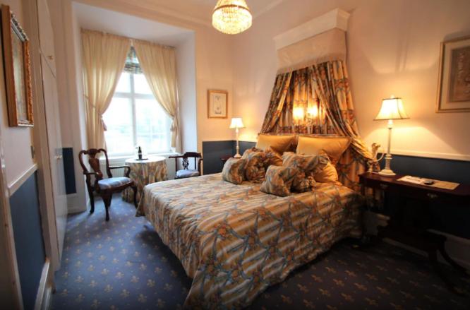 a bedroom with a bed and a desk and a window at Hvedholm Slotshotel in Faaborg