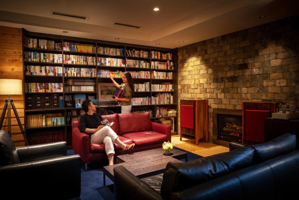 a woman standing in a library with a man sitting on a couch at Villa Concordia Resort & Spa in Hakodate