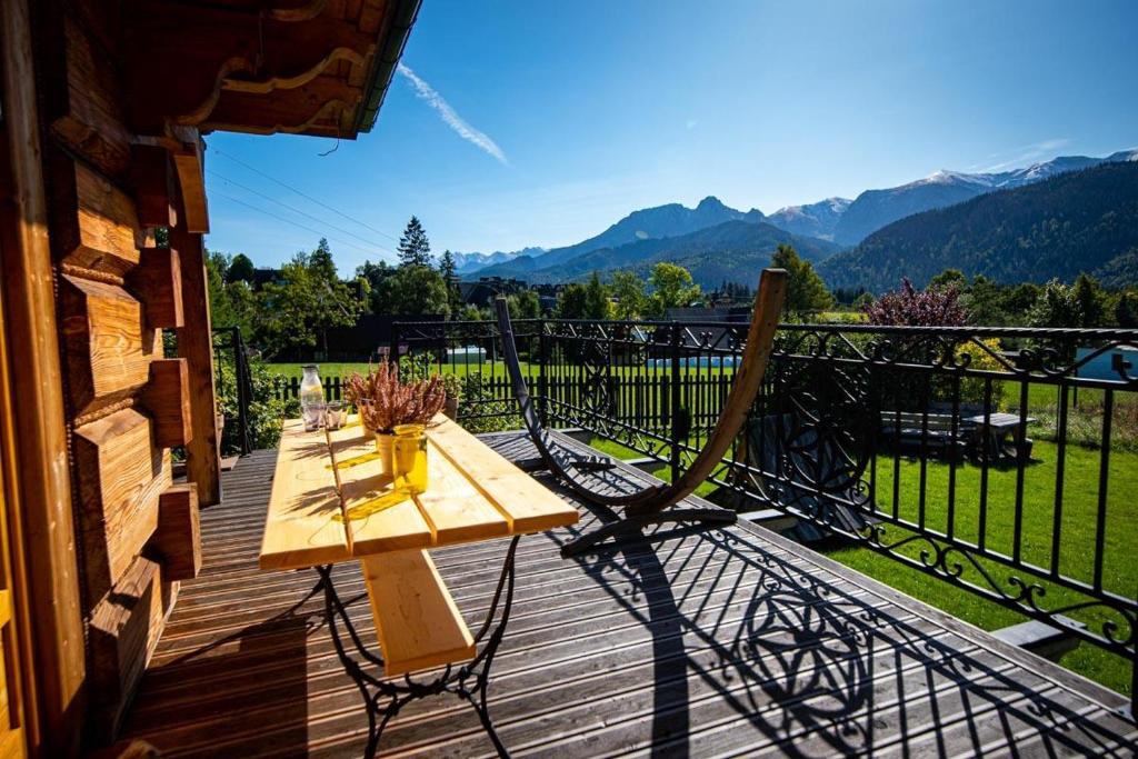 a wooden table on a deck with a view of mountains at Villa z widokiem na Giewont in Kościelisko