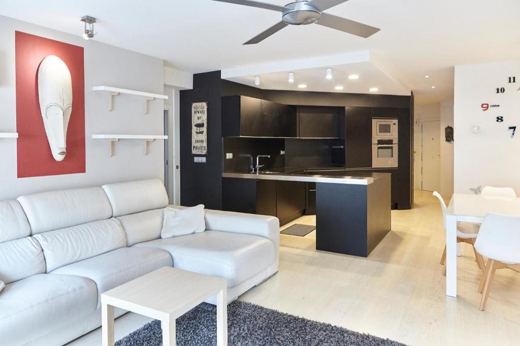 Arana Apartment by BasqueHomes في سان سيباستيان: غرفة معيشة مع أريكة بيضاء ومطبخ
