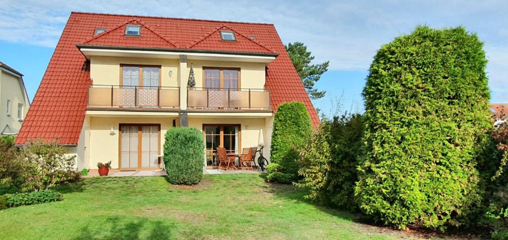 una casa con techo rojo y patio en Ferienwohnung Gartentraum mit tollem Rasengarten, en Ostseebad Karlshagen