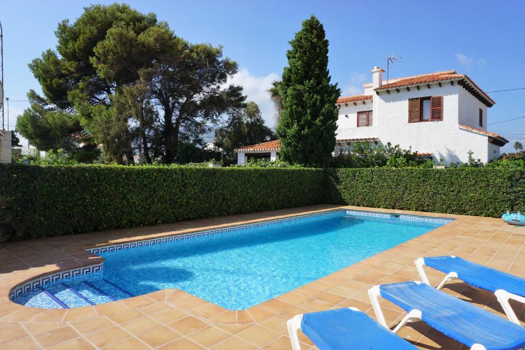 - une piscine avec 2 chaises et une maison dans l'établissement Bungalow PUEBLO MAR en Els Poblets., à Dénia