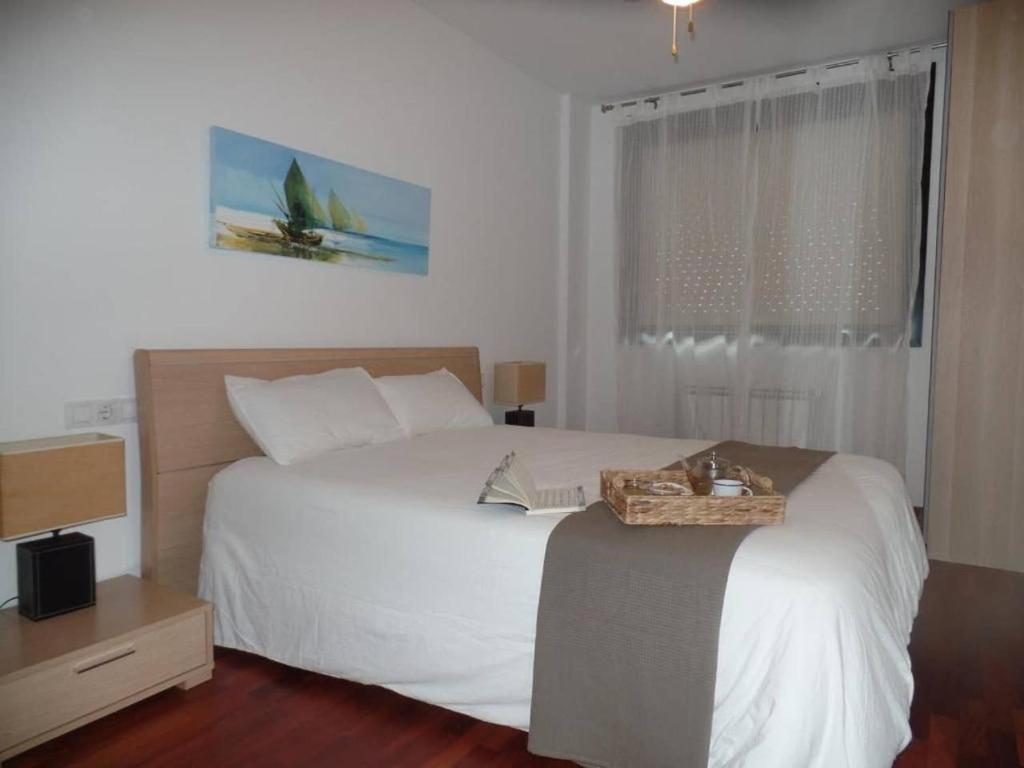 Un dormitorio con una gran cama blanca y una ventana en PISO ACOGEDOR EN SADA COZY FLAT IN SADA WiFi, en Sada
