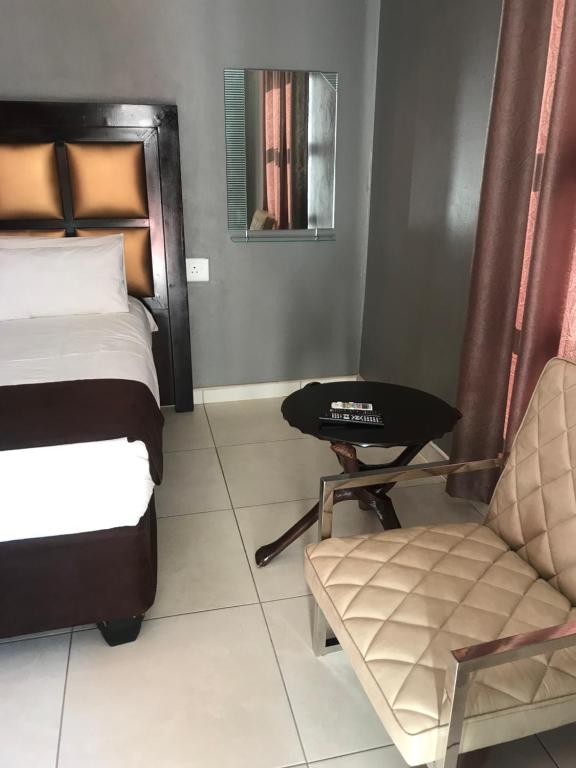 - une chambre avec un lit, une chaise et une table dans l'établissement Venice royal lodge, à Thohoyandou