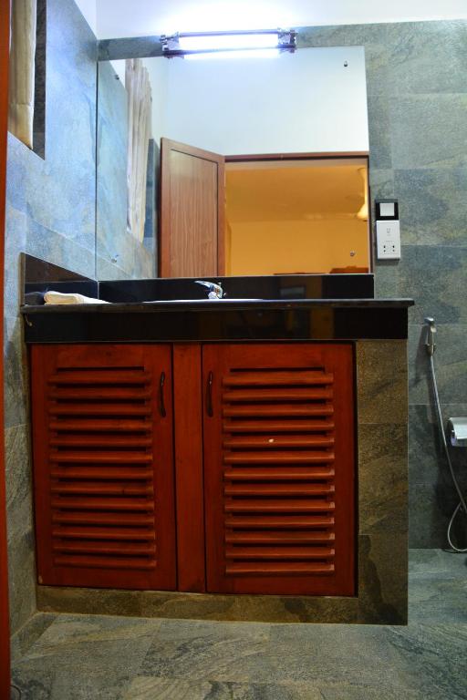 a bathroom counter with a sink and a mirror at Gloria Grand Hotel in Unawatuna