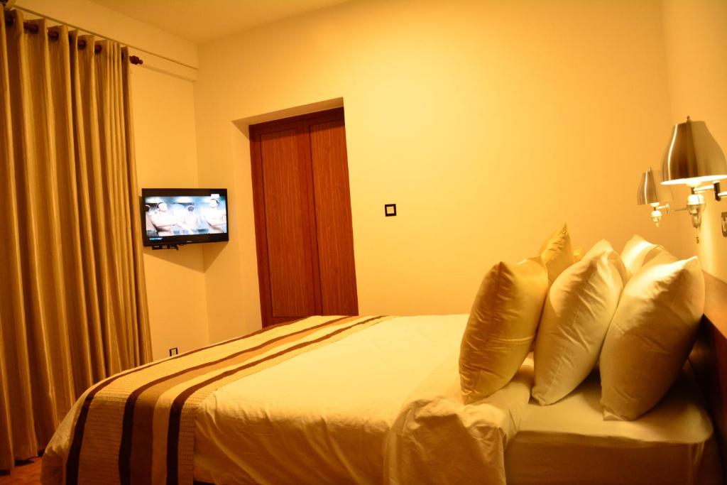a hotel room with a bed with pillows and a television at Gloria Grand Hotel in Unawatuna