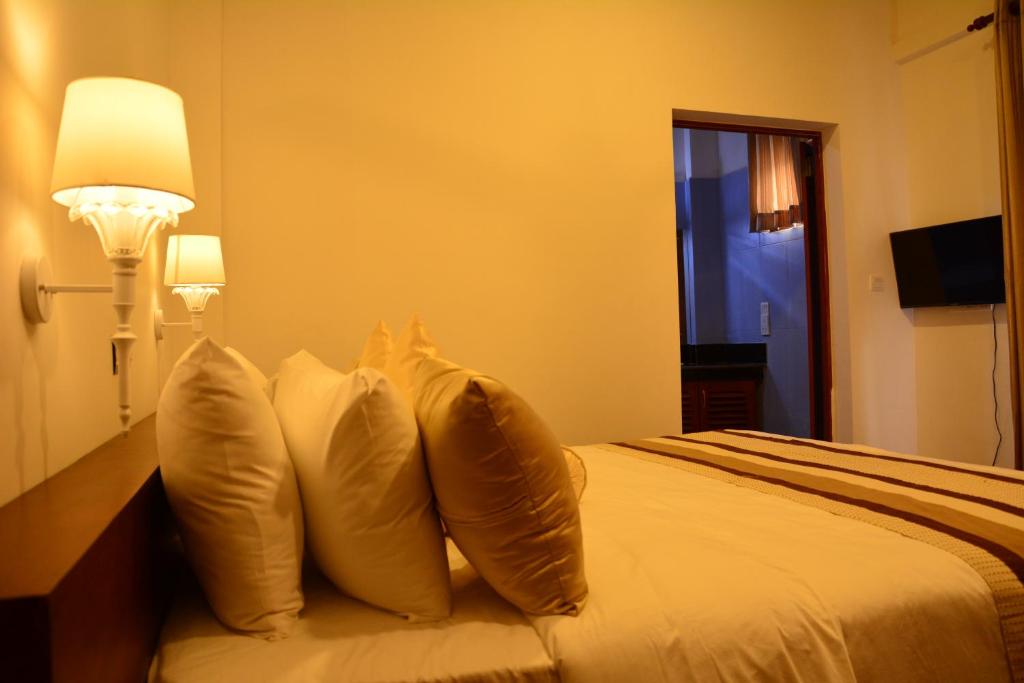 a hotel room with a bed with four pillows at Gloria Grand Hotel in Unawatuna