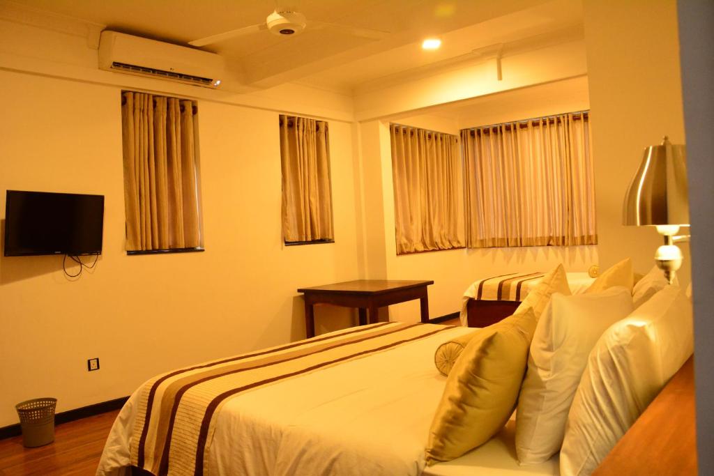 a hotel room with a bed and a television at Gloria Grand Hotel in Unawatuna