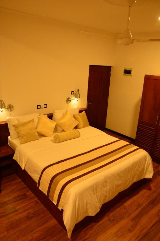a bedroom with a large bed with white sheets at Gloria Grand Hotel in Unawatuna