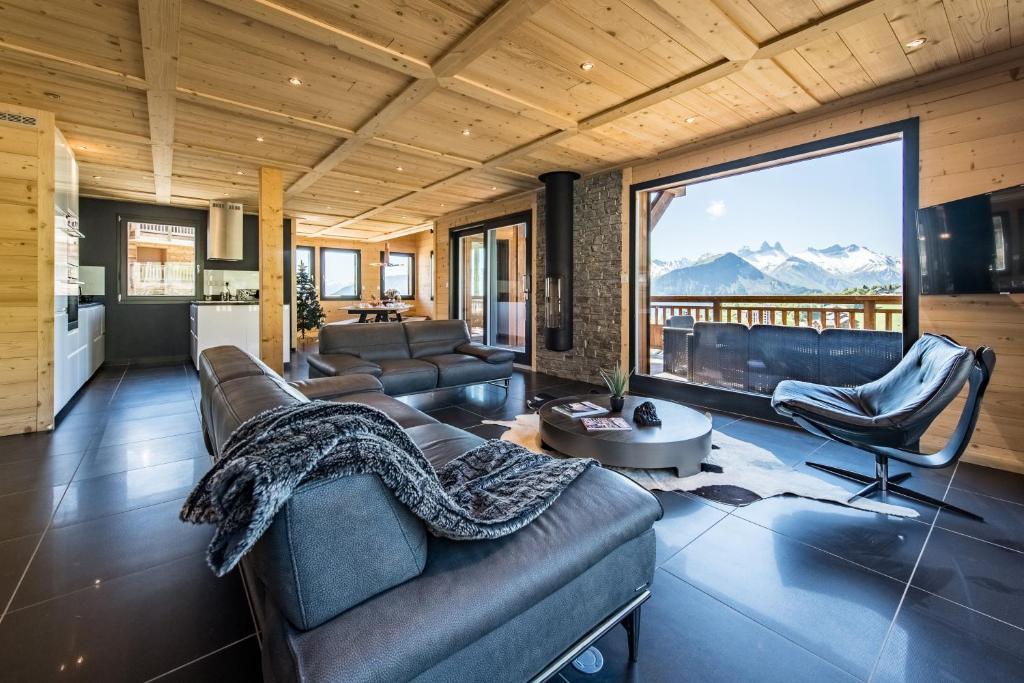 a living room with leather furniture and a large window at Harfang des Neiges in La Toussuire
