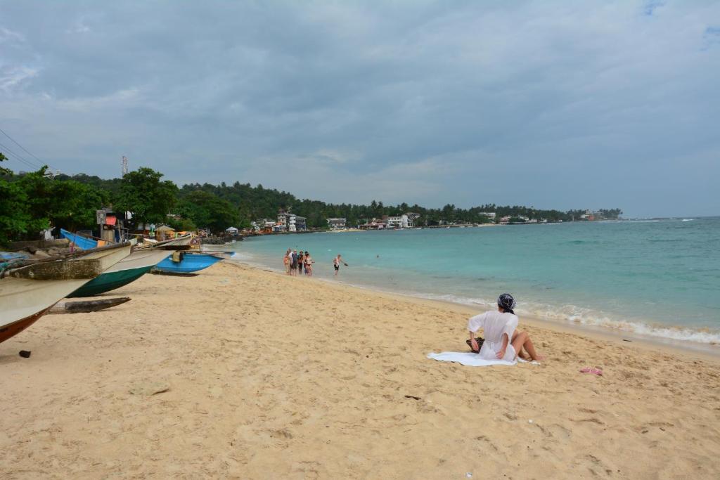 a person sitting on a towel on the beach at Gloria Grand Hotel in Unawatuna