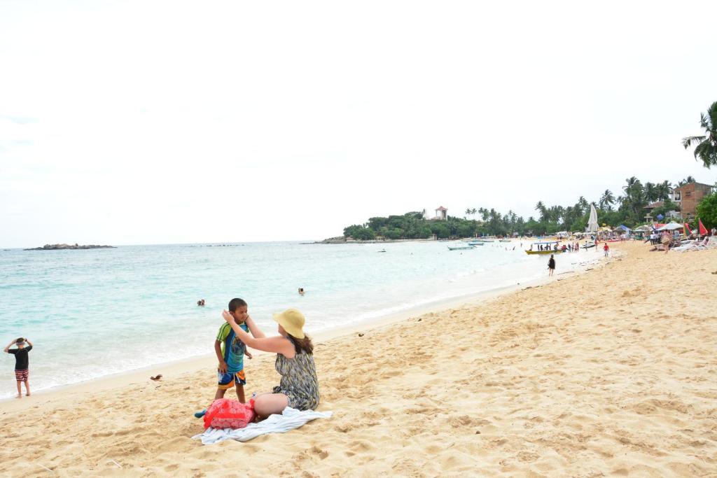 a man and a woman on the beach at Gloria Grand Hotel in Unawatuna