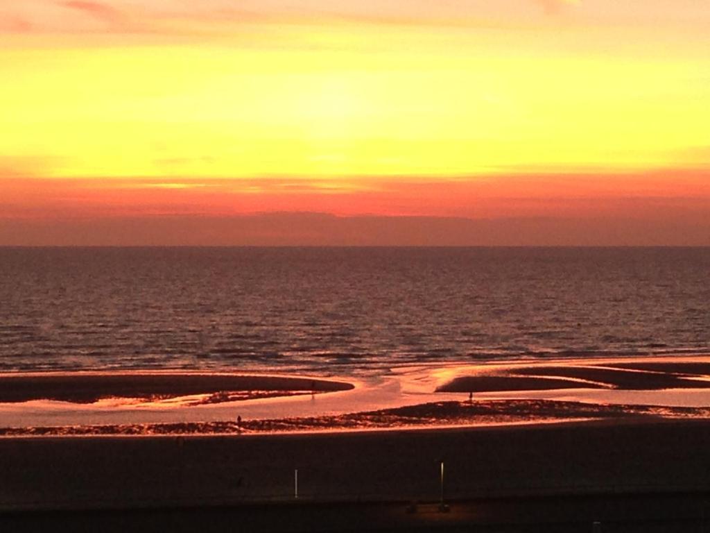 - un coucher de soleil sur l'océan et une plage de sable dans l'établissement Studio Face Mer, à Le Touquet-Paris-Plage