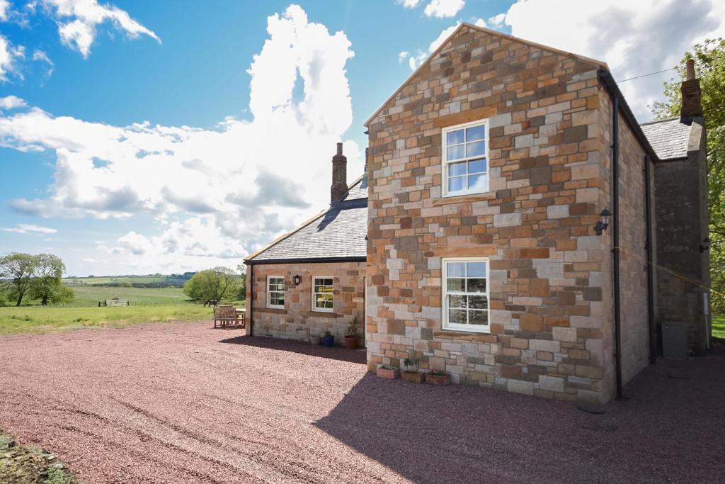 a brick building on a dirt road next to a field at Countryside Escape - The Night Owl in Alnwick