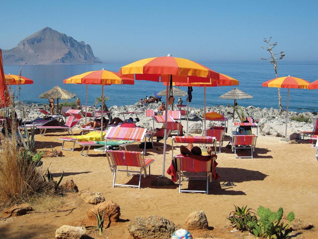 a group of chairs and umbrellas on a beach at Happy Camp Mobile Homes in El-Bahira Camping Village in San Vito lo Capo