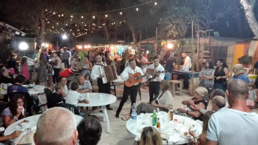 grupa ludzi oglądających zespół grający na imprezie w obiekcie Happy Camp Mobile Homes in El-Bahira Camping Village w mieście San Vito lo Capo