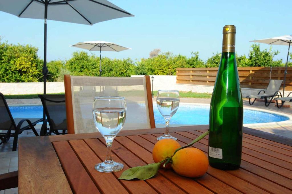 Una botella de vino y dos copas en una mesa de madera. en Citrus Grove Villa, en Argaka