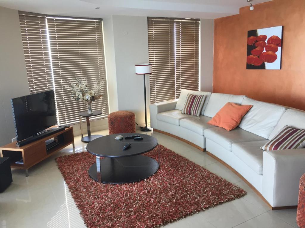 ein Wohnzimmer mit einem weißen Sofa und einem Tisch in der Unterkunft Hibernian Towers 1802 Self Catering Accommodation Strand Western Cape South Africa in Strand