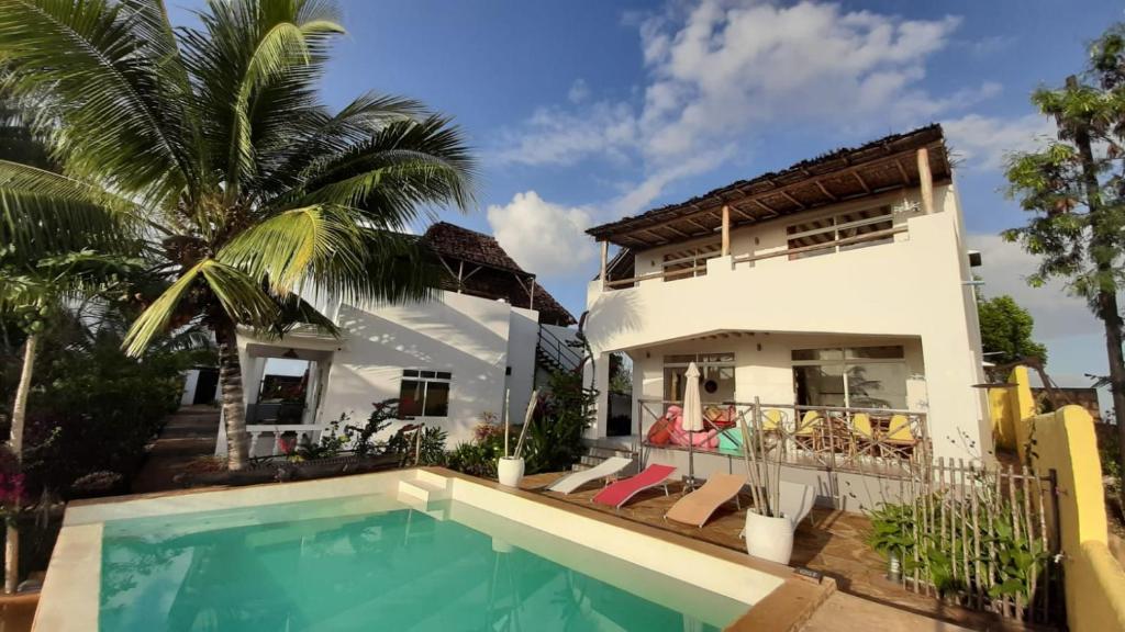 a villa with a swimming pool in front of a house at Maisha Marefu Apartments in Kiwengwa