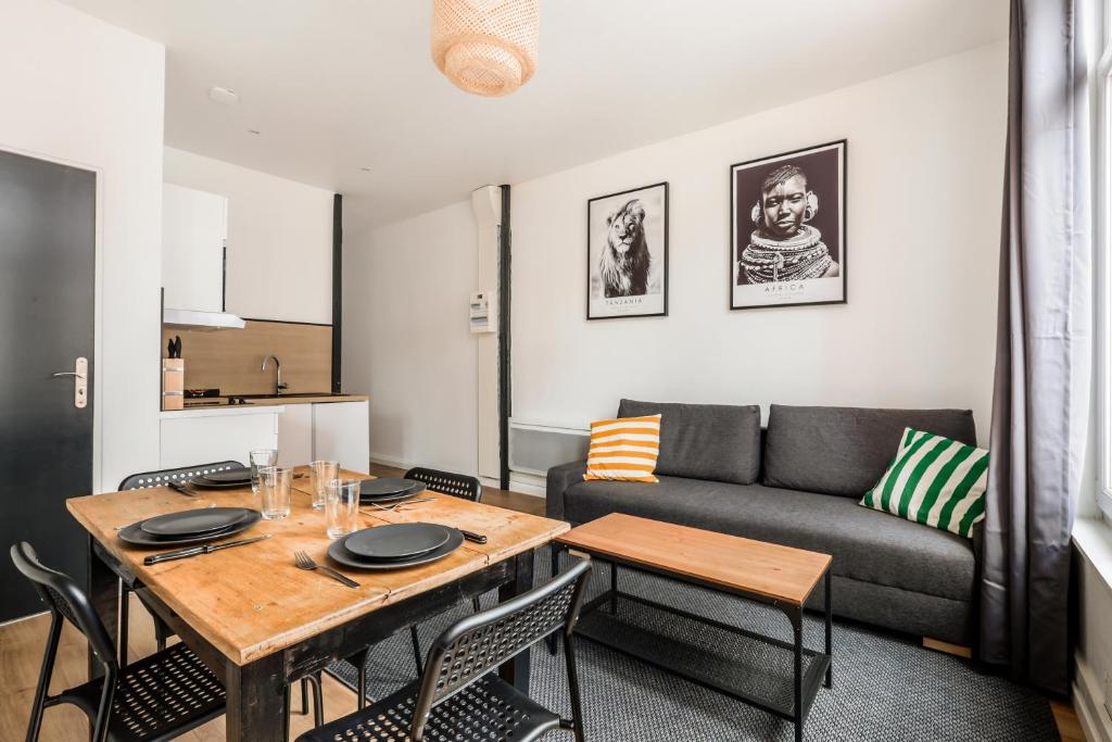 een woonkamer met een tafel en een bank bij Cosy appartement proche gares #2 in Lille