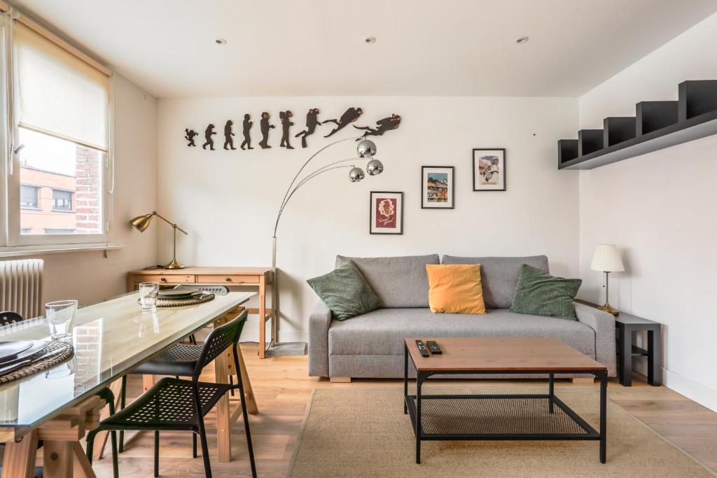 uma sala de estar com um sofá e uma mesa em Appartement Croisé Laroche 40m2 em Marcq-en-Baroeul