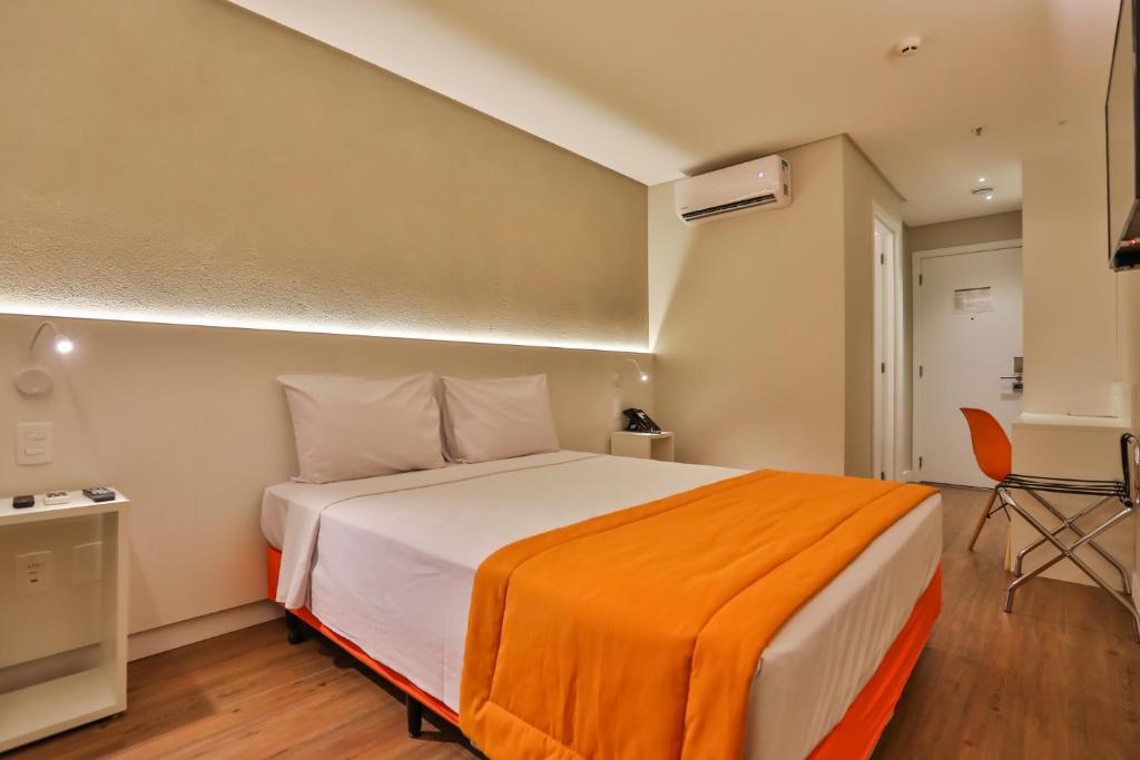 1 dormitorio con 1 cama grande con manta naranja en Go Inn Serra, en Serra